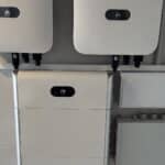 White electrical inverters mounted on a wall, used for solar power systems.