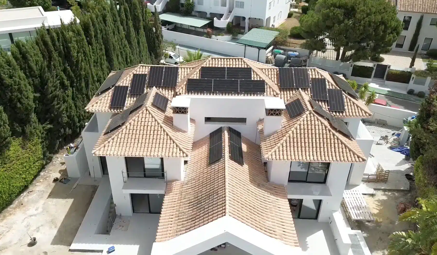 Aerial view of a large white villa with multiple tiled roofs and surrounding greenery.