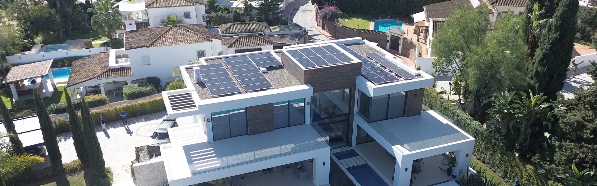 Modern house with large solar panels installed on the flat roof under bright daylight.