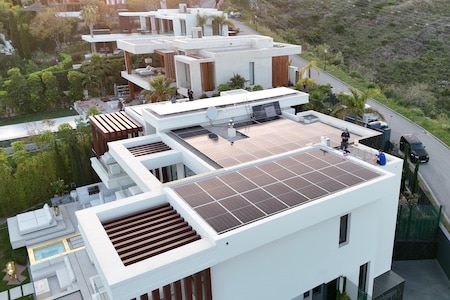 Modern white building with flat roofs and solar panels installed on one of the rooftops.