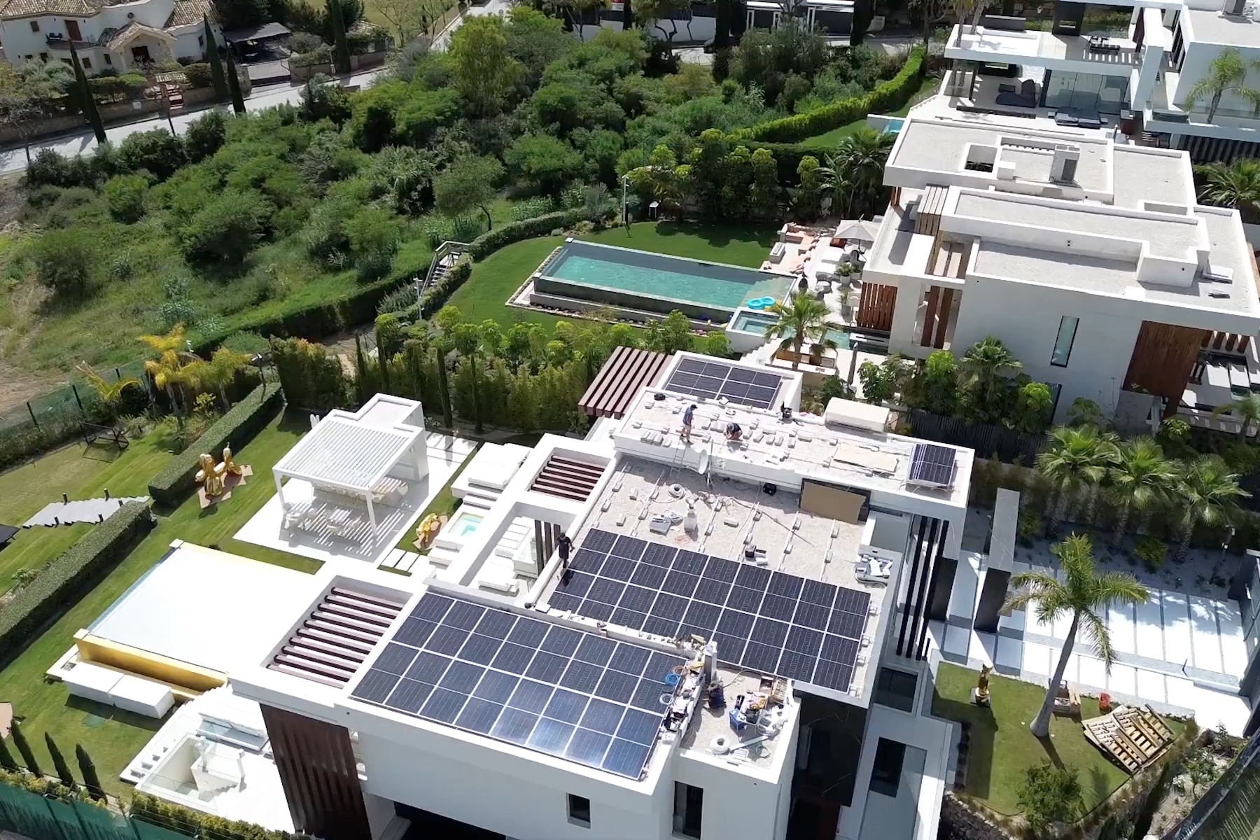 A rooftop covered with solar panels overlooking a green park and swimming pool.