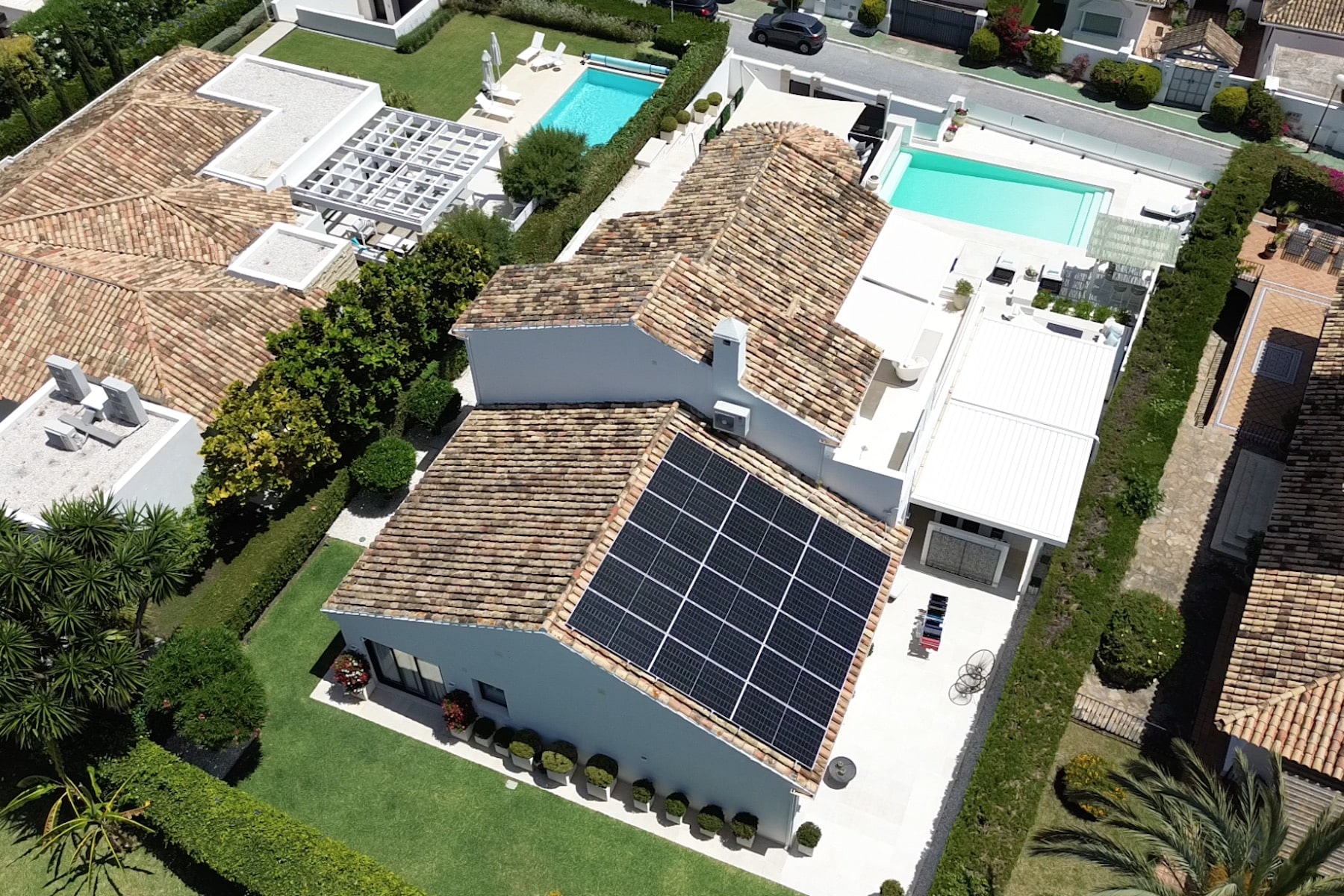 Aerial view of a house with solar panels on the roof, a swimming pool, and a well-maintained yard.